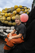 Fisher posing on boat in front of nets, California Market Squid